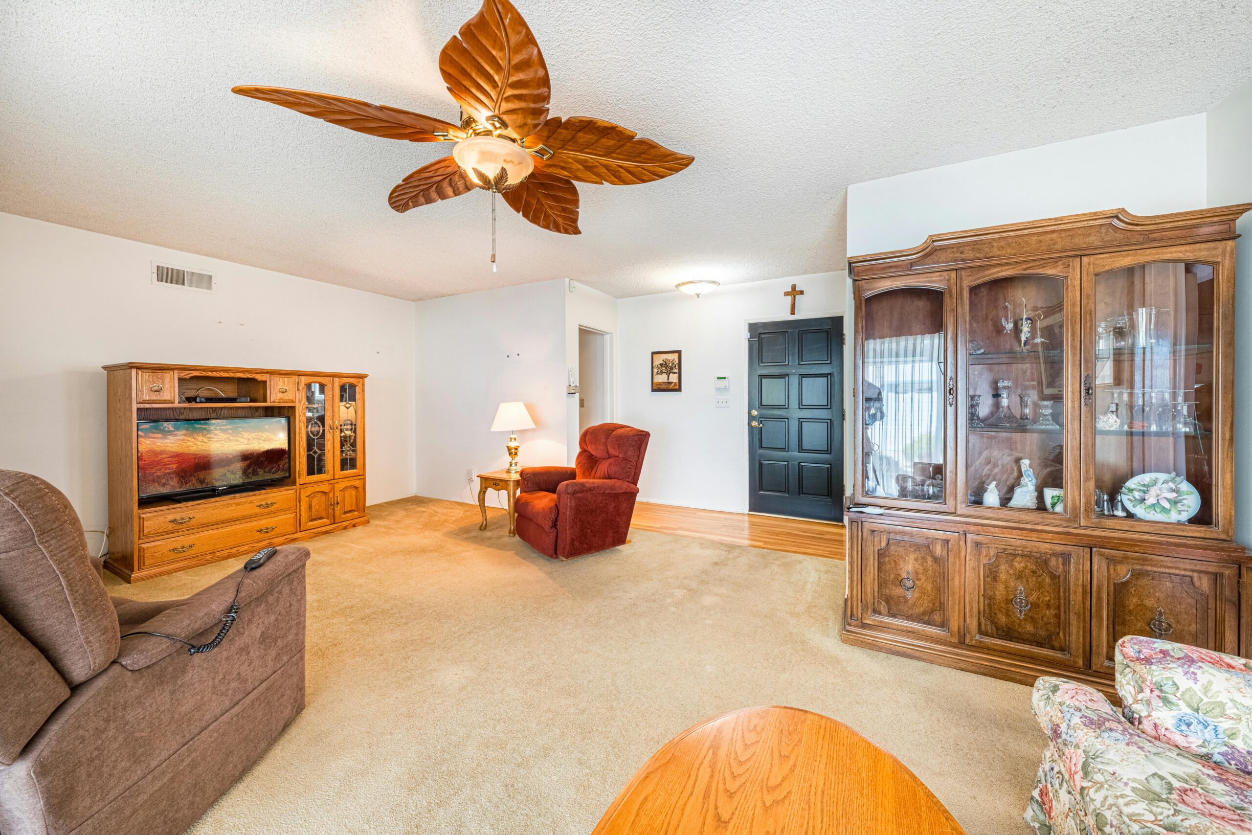 A warm and inviting living room with vintage furniture and ceiling fan.